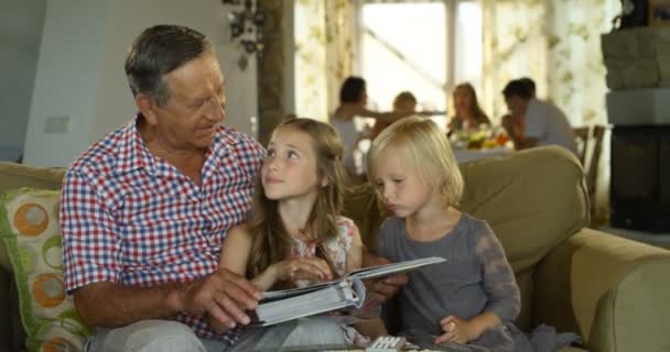 Abuelo mirando viejos álbumes de fotos con dos de sus nietos — Vídeo de stock