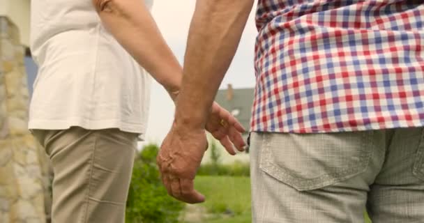 Primer plano de las manos de pareja mayor que se mantienen juntas al aire libre . — Vídeos de Stock