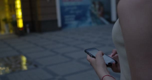 Mujer joven caminando de las manos usando el teléfono inteligente a mensaje de texto — Vídeos de Stock