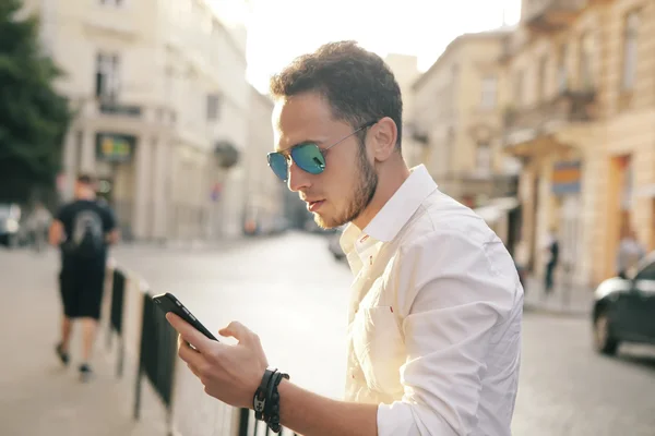 Açık cep telefonu sokak ile modern genç adam portresi.
