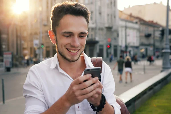 Açık cep telefonu sokak ile modern genç adam portresi.