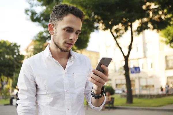 Açık cep telefonu sokak ile modern genç adam portresi.