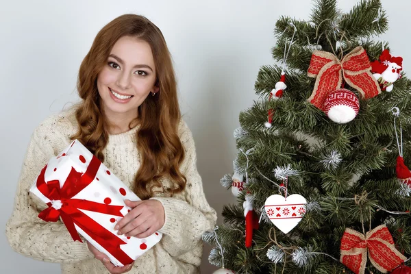 Joyeux jeune femme avec présent dans ses mains près du sapin de Noël — Photo