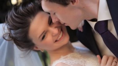 Güzel genç çift gelin ve damat güneşte bir gelinlik içinde şefkatle birbirlerine mutlu aile öpüşme bakarak, yavaş hareket yakın loveshot