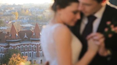 wonderful rich bride and groom look at each other on the terrace on the background at sunset on a sunny warm Lviv city Shot in slow motion  close up