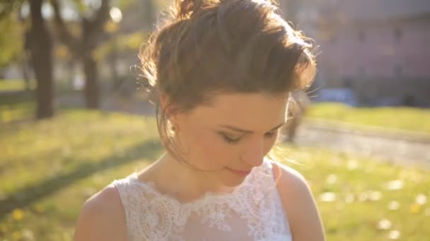 Young beautiful bride standing in the park  and straightens hair shot in slow motion  close up — Stockvideo