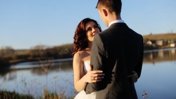 Casamento casal abraçando pelo lago na queda tiro em câmera lenta de perto — Vídeo de Stock