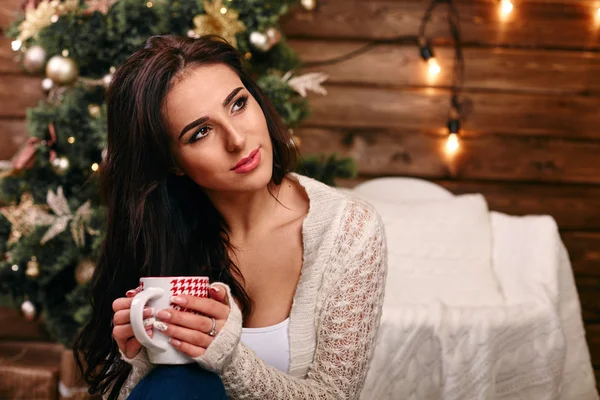 Mujer joven feliz con taza delante de las luces de Navidad — Foto de Stock