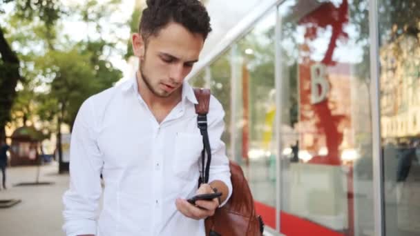 Joven tratando de encontrar un contacto en el teléfono celular. Hombre europeo pasar páginas en el teléfono inteligente . — Vídeo de stock