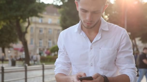 Un uomo che usa il telefono in citta '. Hipster toccando smartphone nel bel mezzo di un centro città . — Video Stock