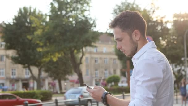 Estudiante enviando un mensaje de texto por teléfono en el centro de la ciudad . — Vídeos de Stock