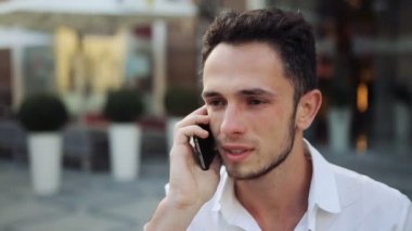 Dinleme ve gülümseyen telefon üzerinde tutarak çekici bir adam. Genç erkek telefonda sohbet ederken olumlu bir tepki var.