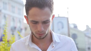 Bir kare ve manifatura onun smartphone üzerinde oturan genç bir adam. Yakın çekim yakışıklı bir ekran dokunarak. Cep telefonu kullanarak bir ileti oluşturma.