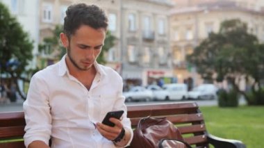Genç Meydanı'nda oturan ve onun smartphone tutan adam. Cep telefonu kullaranarak onun 20s erkek.
