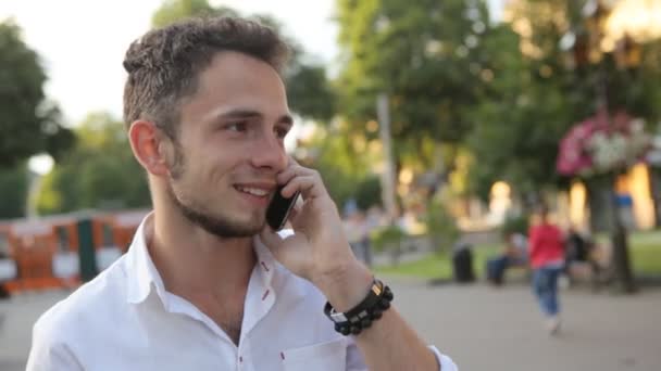 . gars positif animé parle sur téléphone portable à l'extérieur et sourire . — Video