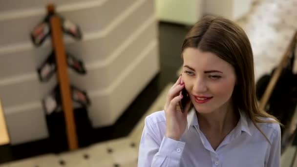 Csodálatos lány piros ajkak és a piros körömlakk beszél a mobilján a bevásárlóközpontban — Stock videók