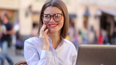 Kırmızı dudaklar ile çekici Bayan gülümseyerek onu cep telefonundan konuşuyor ve onu laptop kullanma