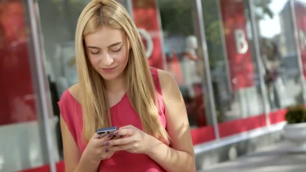 Cute blonde chatting with her friends using phone on the street — Stock Video