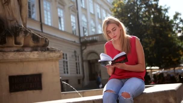 市内中心部に彼女の本を読みながら笑顔のきれいな女性 — ストック動画