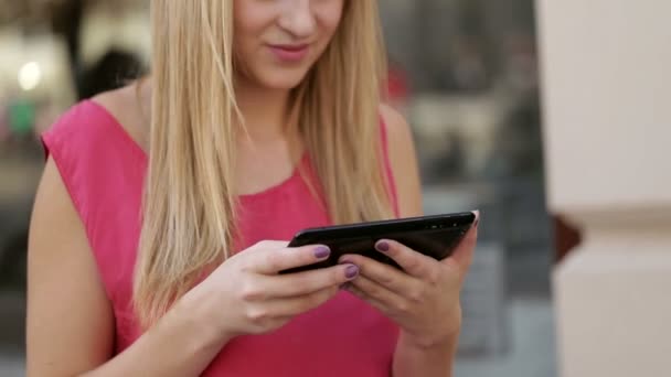 Jonge dame geconcentreerd in communicatie met haar vriendje via digitale tablet op de straat — Stockvideo