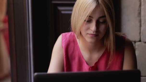 Giovane ragazza che lavora con il computer portatile e seduto al caffè — Video Stock