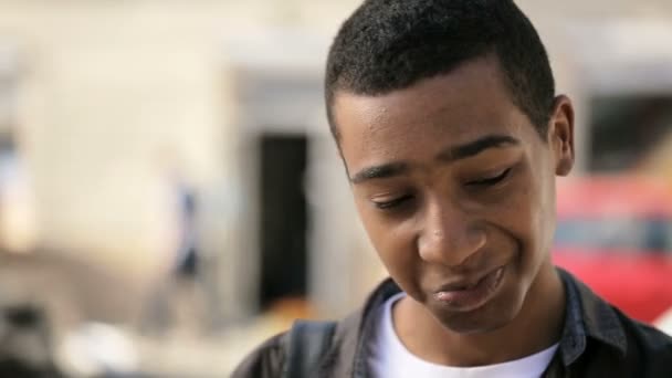 Sonriente joven con camiseta blanca y camisa negra está hablando en su teléfono inteligente en la calle — Vídeos de Stock