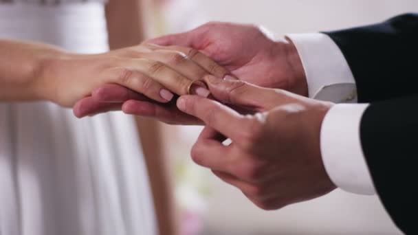 Золотые обручальные кольца и руки только что женатой пары Крупным планом на руку мужчина надел обручальное кольцо на палец невесты, снято на Красную цифровую камеру кино в 4K — стоковое видео