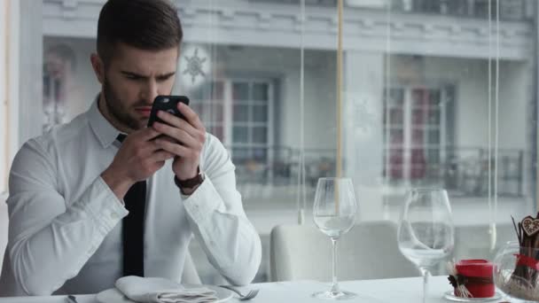Портрет красивого чоловіка, який використовує смартфон на відкритому повітрі в ресторані — стокове відео