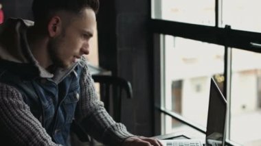 20'li kızlarında bir erkek kafede çalışıyor. Çekici adam multitasking adam cep telefonu konuşuyor ve dizüstü bilgisayarda yazarak.