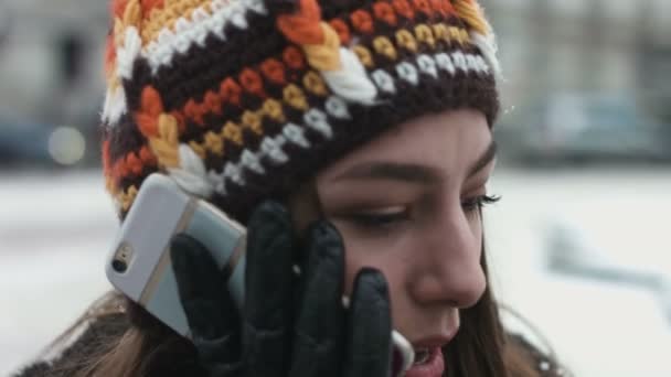 Közeli kép: egy lány beszél a mobiltelefon kültéri téli napon. Fiatal nő van egy édes beszélgetés a telefon, miközben vár egy időpontot. — Stock videók