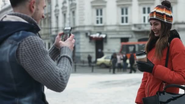 Νεαρός άνδρας λαμβάνοντας εικόνες από τη νέα φίλη του στο smartphone. Τύπος χρησιμοποιεί κάμερα στο κινητό του. Ελκυστικές κορίτσι που παρουσιάζουν για την καλύτερη εικόνα. — Αρχείο Βίντεο