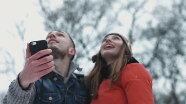 Momento romántico de una dulce pareja haciendo selfie mientras los pájaros vuelan sobre el cielo. Hombre y mujer en sus 20 años tomando fotos en dispositivo móvil al aire libre en el invierno . — Vídeos de Stock