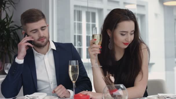 Jeune femme ennuyé à ce jour tandis que son petit ami ayant téléphone portable d'affaires, homme occupé à utiliser leurs téléphones intelligents au restaurant — Video