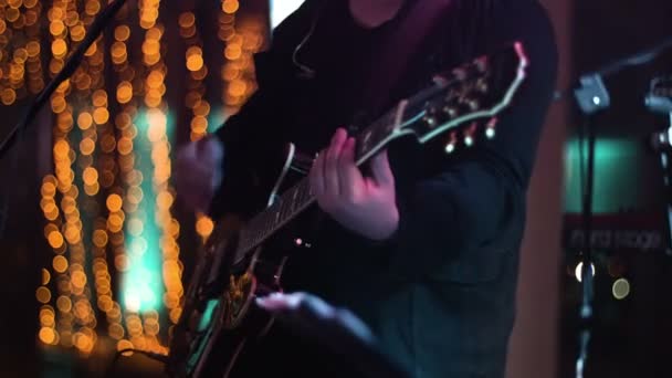 Bijgesneden beelden van muzikant spelen op de gitaar op het podium tijdens late night show in de nachtclub. Middellange schot. — Stockvideo