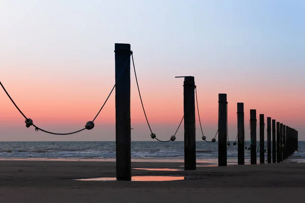 Gün batımında Middelkerke, Belçika yakınlarındaki Lombardsijde plajında kazık kafaları.