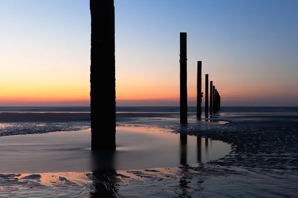 Gün batımında Middelkerke, Belçika yakınlarındaki Lombardsijde plajında kazık kafaları.