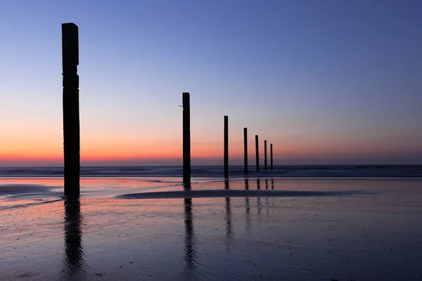Gün batımında Middelkerke, Belçika yakınlarındaki Lombardsijde plajında kazık kafaları.