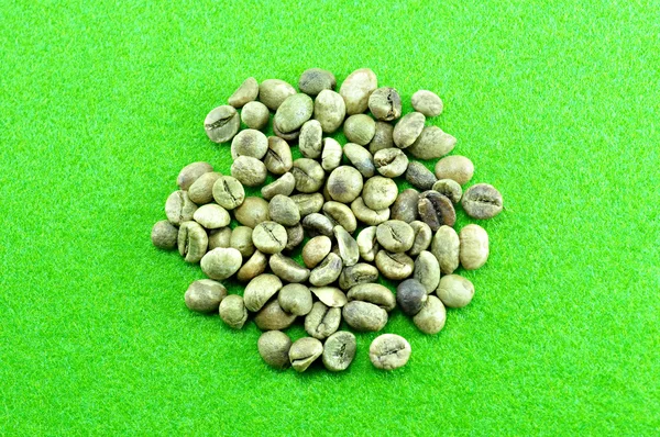 Surowe ziarna kawy na zielonym tle — Zdjęcie stockowe