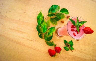 A glass of strawberry smoothie cocktail with mint and herbs on a