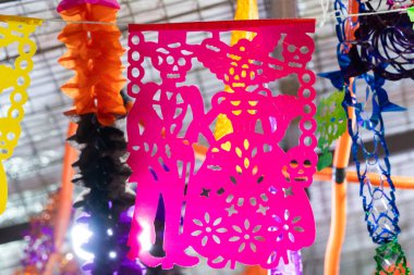 Üzerinde bir iskelet ve bir kadın olan pembe bir kağıt. İskelet bir gitar tutuyor. Meksika Ölüler Günü geleneği, adaklar, yemek, renkler, dekorasyonlar ve papel picado, La Catrina.