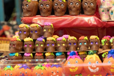 Çikolata kafatası ve balkabağı gösterisi. Kafatasları çiçeklerle süslenmiş. Meksika Ölüler Günü geleneği, adaklar, yemek, renkler, dekorasyonlar ve papel picado, La Catrina.