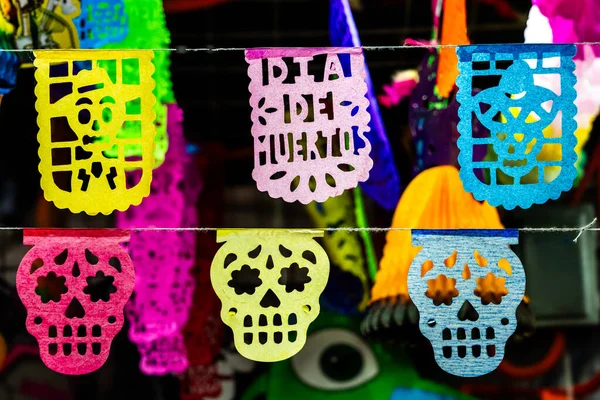 Üzerinde Dia De Muertos yazıları olan canlı bir kağıt kafatası gösterisi. Meksika Ölüler Günü geleneği, adaklar, yemek, renkler, dekorasyonlar ve papel picado, La Catrina.