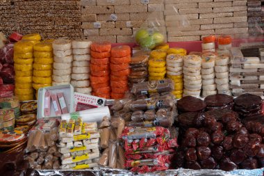 Bir masanın üzerinde çeşitli renkli abur cuburlar sergilenir. Atıştırmalıklar meyve karışımını içeriyor. Meksika Ölüler Günü geleneği, adaklar, yemek, renkler, dekorasyonlar ve papel picado, La Catrina.