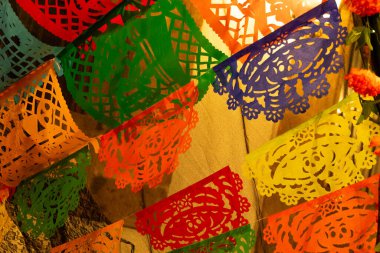 Tavandan sarkan renkli bir dizi kağıt fener. Fenerlerin renkleri farklı. Meksika Ölüler Günü geleneği, adaklar, yemek, renkler, dekorasyonlar ve papel picado, La Catrina.