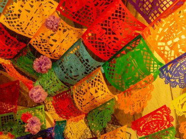 Üzerinde çiçekler olan renkli bir kağıt fener gösterisi. Renkler parlak ve neşeli. Meksika Ölüler Günü geleneği, adaklar, yemek, renkler, dekorasyonlar ve papel picado, La Catrina.