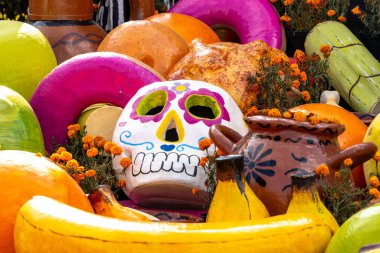 Bir kafatası muz, portakal ve elma gibi çeşitli meyve ve sebzelerle çevrilidir. Meksika Ölüler Günü geleneği, adaklar, yemek, renkler, dekorasyonlar ve papel picado, La Catrina.