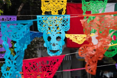 Ortasında büyük bir kafatası olan canlı bir kağıt fener gösterisi. Meksika Ölüler Günü geleneği, adaklar, yemek, renkler, dekorasyonlar ve papel picado, La Catrina.