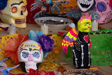 Kafasında çiçek olan bir kafatası ve adı Cuma olan çeşitli dekorasyonlarla kaplı bir masa. Meksika Ölüler Günü geleneği, adaklar, yemek, renkler, süslemeler ve Aziz Catrina.