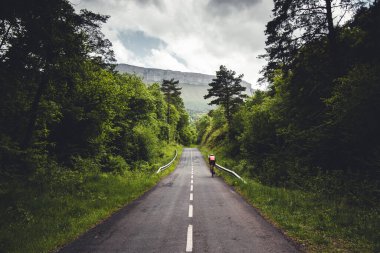 Bask ülkesindeki Aiaraldea Vadisi 'nden bir bisikletçi büyük bir manzarada rpad boyunca yürüyor.