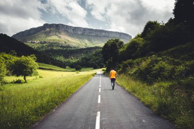 Bask ülkesindeki Aiaraldea Vadisi 'nden büyük bir manzarada bir rampa boyunca yürüyen bir adam..